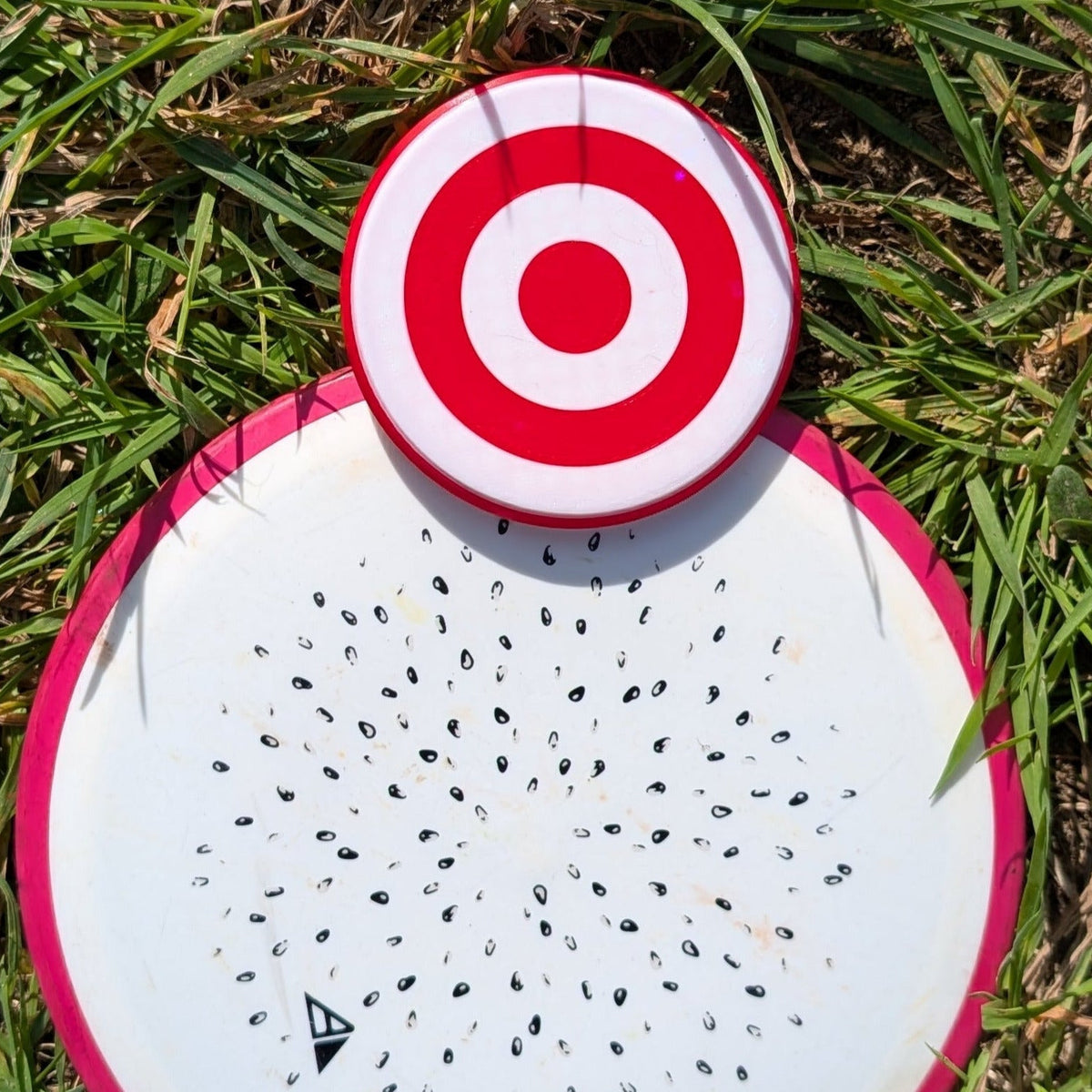Disc golf disc with a red and white disc golf mini marker on the front