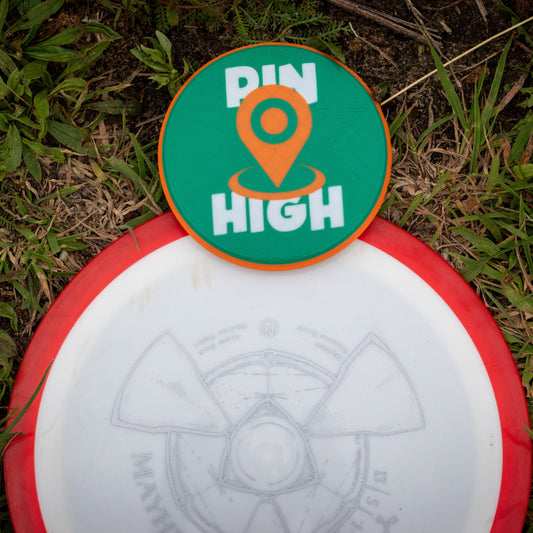 Disc golf disc with 'Pin High' disc golf mini marker on grass
