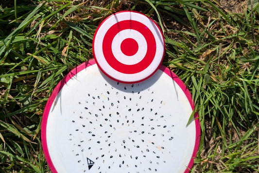 Disc golf disc with a red and white disc golf mini marker on the front